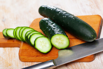 Cut fresh green cucumbers on wooden background, nobody