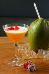 Caipirinha brazilian typical coktail, exotic tropical flavor coconut water blend mango fruit juice syrup with flower petals, served on fresh ice cold glass. Beautiful colorful drink on close up view.