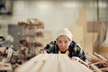 Woman stacking wood planks at the workshop