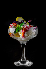 Tasty ice cream decorated by fruits in glass on black background