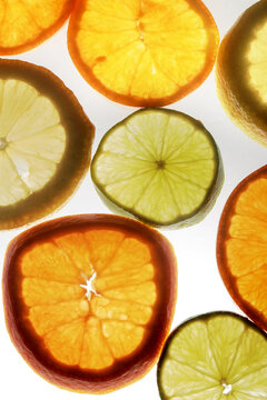 composici&oacute;n de lonjas de lima limon y naranja con fondo blanco y luz por detras