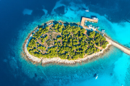 Aerial view of beutiful small island in sea bay at sunny day in summer in Murter, Croatia. Top view of transparent blue water, green trees, mountain, sandy beach, boats and yachts. Tropical landscape