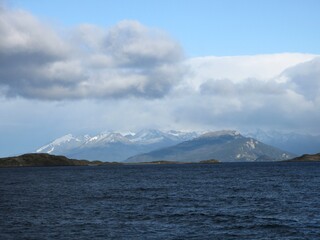 Fototapeta na wymiar View of Tierra del Fuego (Land of Fire) and the Beagle Channel - blue water, snow-capped mountains and grey clouds, Argentina 