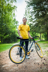 Naklejka premium Portrait of a young man moving on a Bicycle. In a public Park, among trees and vegetation.