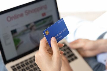 Close up female hand holding plastic credit card, woman buyer paying money online, using laptop, customer making internet secure payment, browsing banking service, ecommerce concept