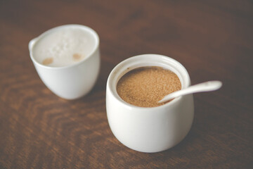 small cup with cappuccino next to sugar bowl