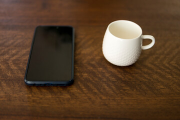 Fototapeta na wymiar empty white cup next to smartphone