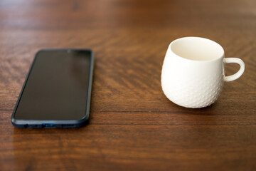 empty white cup next to smartphone