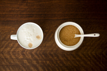 small cup with cappuccino next to sugar bowl