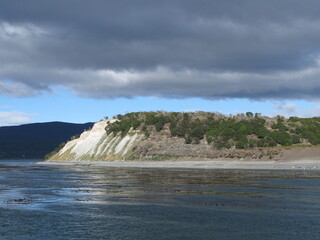 View of Tierra del Fuego (Land of Fire) from the Beagle Channel - blue water and dark clouds, Argentina