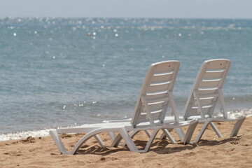 Deck chair in the sand on the shore. Relax, relaxation on the beach. Blue water in the ocean sea.