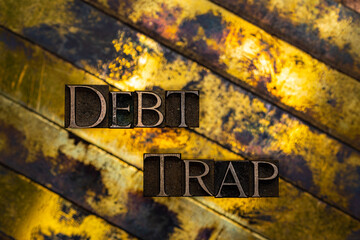 Debt Trap text formed with real authentic typeset letters on vintage textured silver grunge copper and gold background