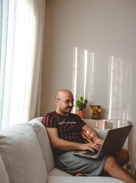 Happy man working with leptop from his home and holding a coffee mug in his hand.