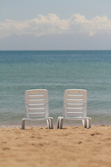 Deck chair in the sand on the shore. Relax, relaxation on the beach. Blue water in the ocean sea.