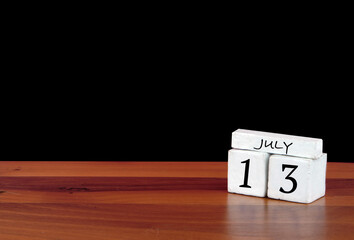 13 July calendar month. 13 days of the month. Reflected calendar on wooden floor with black background
