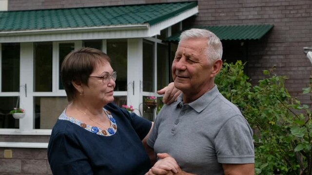 Happy Senior Couple - Man And Woman - Dancing And Laughing Outside By Their House