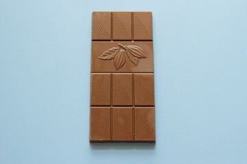 Milk chocolate isolated on blue background from top view. Close up a chocolate bar isolated on blue background.
