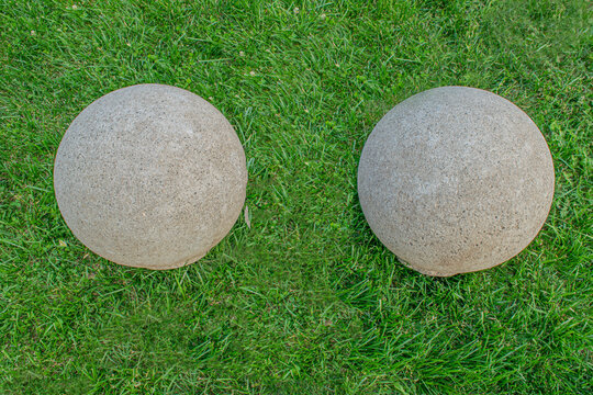 Close-up view of two decorative spherical concrete globes/balls in the green grass. Tbilisi Georgia 