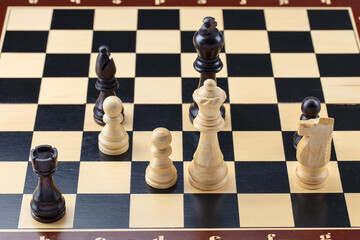 Wooden chess. Chess pieces are located on a chessboard. Black checkmate and win. A chessboard stands on a white background. Close-up