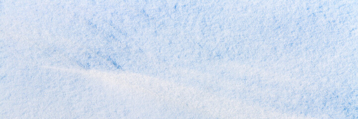 Natural snow texture. Smooth surface of clean fresh snow. Snowy ground. Winter background with snow patterns. Closeup top view. Wide panoramic texture for background and design.
