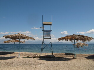 Beach near Perama, Corfu Island, Greece - wicker beach parasols and lifeguard tower