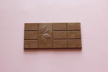 Milk chocolate isolated on pink background from top view. Close up a chocolate bar isolated on pink background.