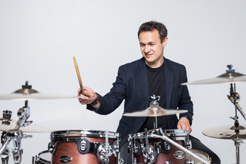 Young drummer behind drum set and plays the drums isolated on white background