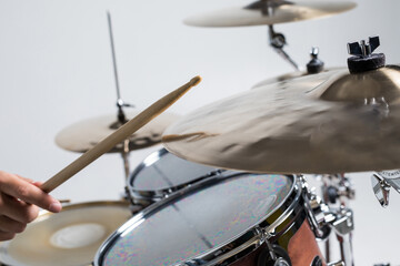 Close up of hands of male drummer holdning drumsticks sitting and playing drums on white background