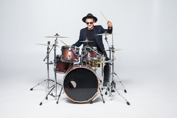 Young man in a suit playing drums isolated on white background