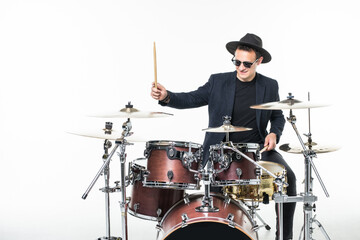 Fototapeta premium Handsome young man behind the drum kit isolated on a white background