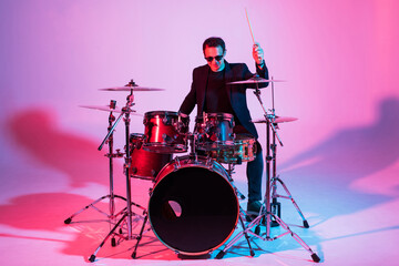 Young man drummer playing on drums on music concert. Club lights, artist show.