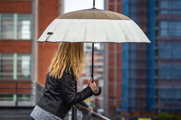 Woman with umbrella standing in rain at city street
