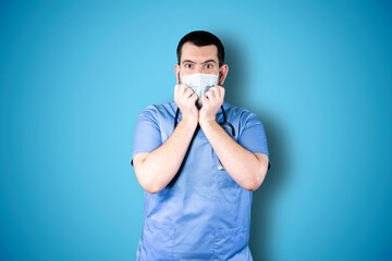 I'm afraid. Fright. Portrait of doctor with mask. Business man standing isolated on trendy blue studio background. Male half-length portrait. Human emotions, facial expression concept