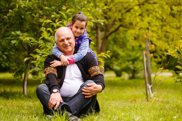 Fototapeta premium Portrait of small girl with senior grandfather in the backyard garden, standing.