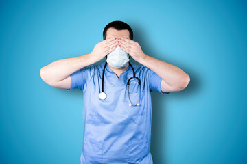 Portrait of a puzzled bearded doctor with mask holding hands on his head isolated over chroma background