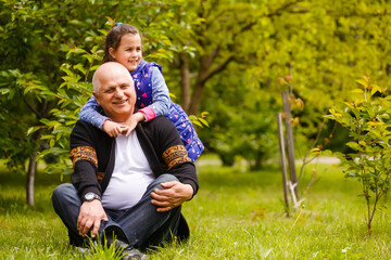 Naklejka na ściany i meble Little girl spending time with grandfather in the park.