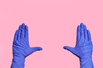 Hands in medical gloves show a frame, measure something. Pink background.