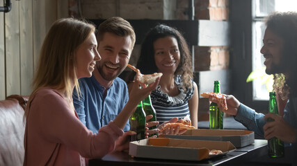Friends or colleagues spend Friday in pub drink beer in bottles eat fresh pizza telling funny stories laughing feels overjoyed. Warm relations, bond friendship of multiethnic millennial people concept