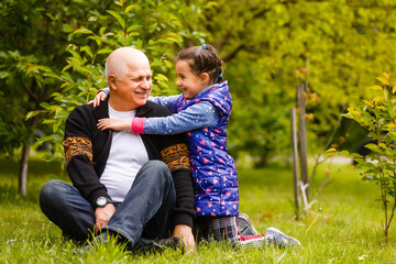 Fototapeta premium Portrait of small girl with senior grandfather in the backyard garden, standing.