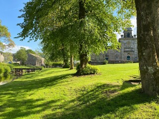 Village green, with old trees, and a footbridge over Linton Beck, in Linton, Skipton, UK
