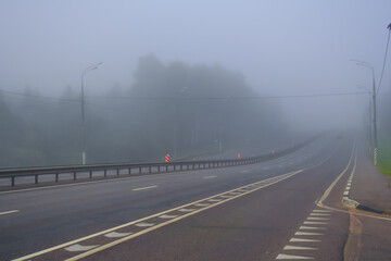 Early morning driving on highway in fog. Autumn, dry weather, foggy grey sky. No vehicle on the road motorway.