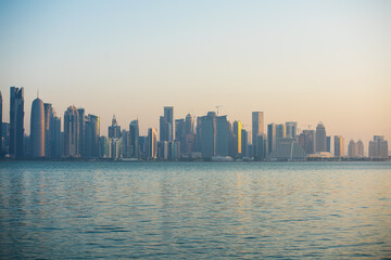 Fototapeta na wymiar Dawn on Doha. View of the city center. The rays of the sun fall on high back at an angle. West Bay