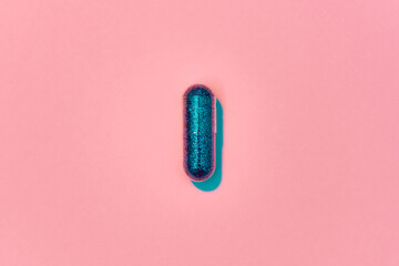 Creative concept with blue glitter pill isolated on pastel pink background. Minimal style, art...