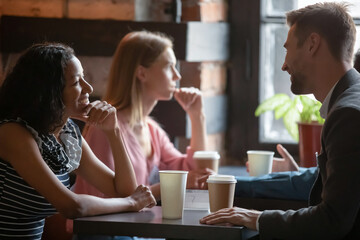 Multi ethnic couples sitting in cafe enjoy chatting, focus on African girl flirting with Caucasian guy during speed dating romantic meeting participation. Love seekers, romantic relationships concept - obrazy, fototapety, plakaty