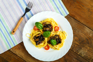 Plate on a napkin nest pasta stuffed with mushrooms and onions with greens next to a fork.
