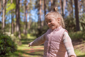 Cute adorable little caucasian child girl enjoy standing in forest during walk .Dreaming and feel free. Freedom lifestyle.