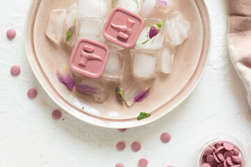 Pink chocolates lie on ice. Place for photo.
