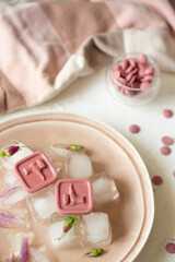 Pink chocolates lie on ice. Place for photo.
