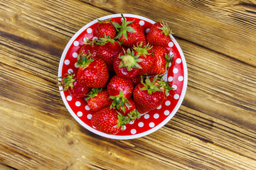 Fresh strawberry in a plate on a wooden table. Top view