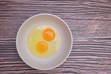 In selective focus top view of a fresh egg in a white bowlon old wooden table background with copy space